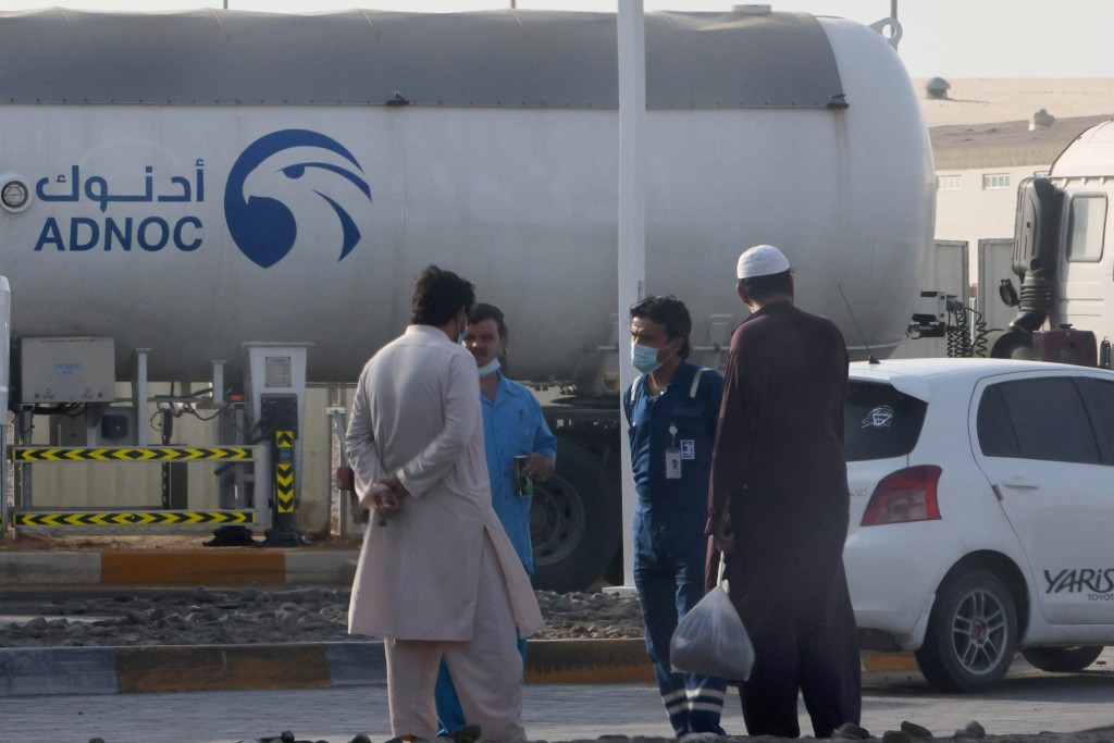 "Men stand next to a tank at a storage facility of oil giant ADNOC in the Msaffah industrial district in the Emiarti capital Abu Dhabi on January 17, 2022. - Three people were killed in a suspected drone attack that set off a blast and a fire in Abu Dhabi today, officials said, as Yemen's rebels announced military operations in the United Arab Emirates. Two Indians and a Pakistani died as three petrol tanks exploded near the storage facility of oil giant ADNOC, while a fire ignited in a construction area at Abu Dhabi airport. (Photo by AFP)"